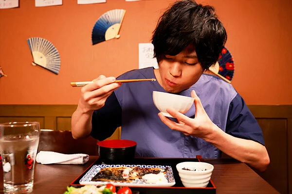 定食を食べながら思索にふける直哉(保志健斗)。何気ない日常が物語の始まりに