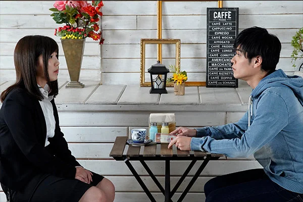 カフェで向き合い、過去を振り返るように真剣な表情で話す二人の姿