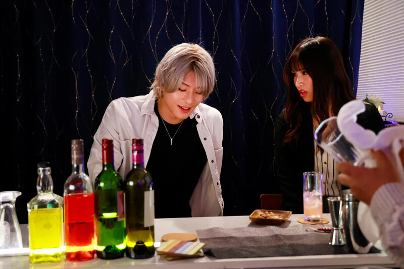 バーカウンターで並ぶ男女。グラス越しの視線と沈黙が、これからの展開を予感させる。