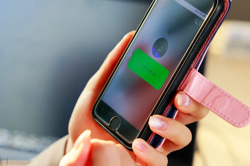 スマートフォンの画面を見つめる女性の手元。迷いと決断が交差するワンシーン。