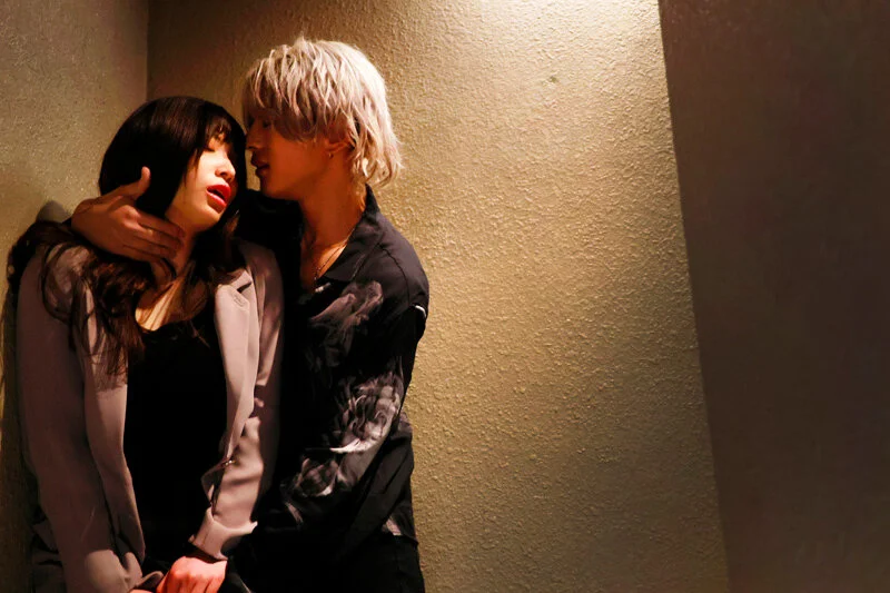 壁際で距離を詰める二人。逃げ場のない近さに、息が詰まるような緊張感が漂う。