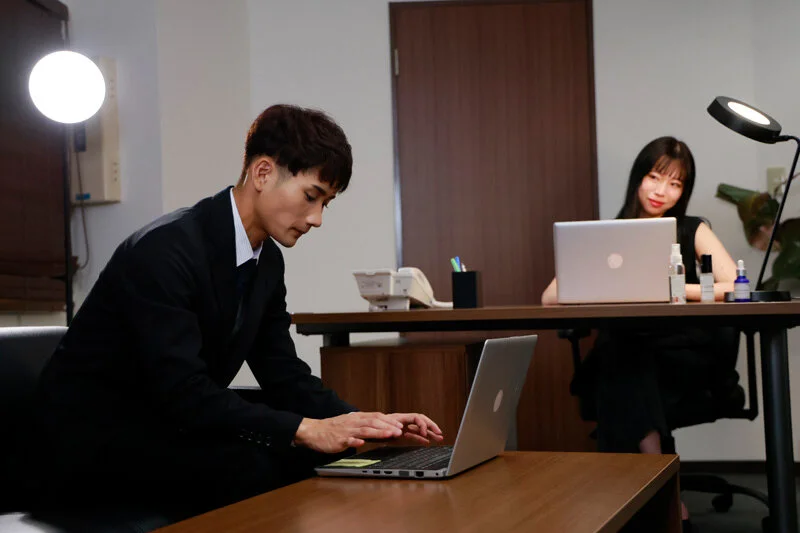 仕事をする彼と、見つめる彼女。視線だけで気持ちが伝わってしまいそうな距離。